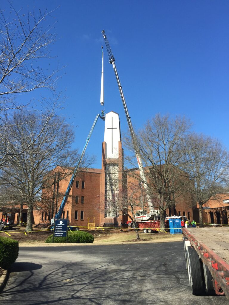 crane lifting a steeple on to the top of a church